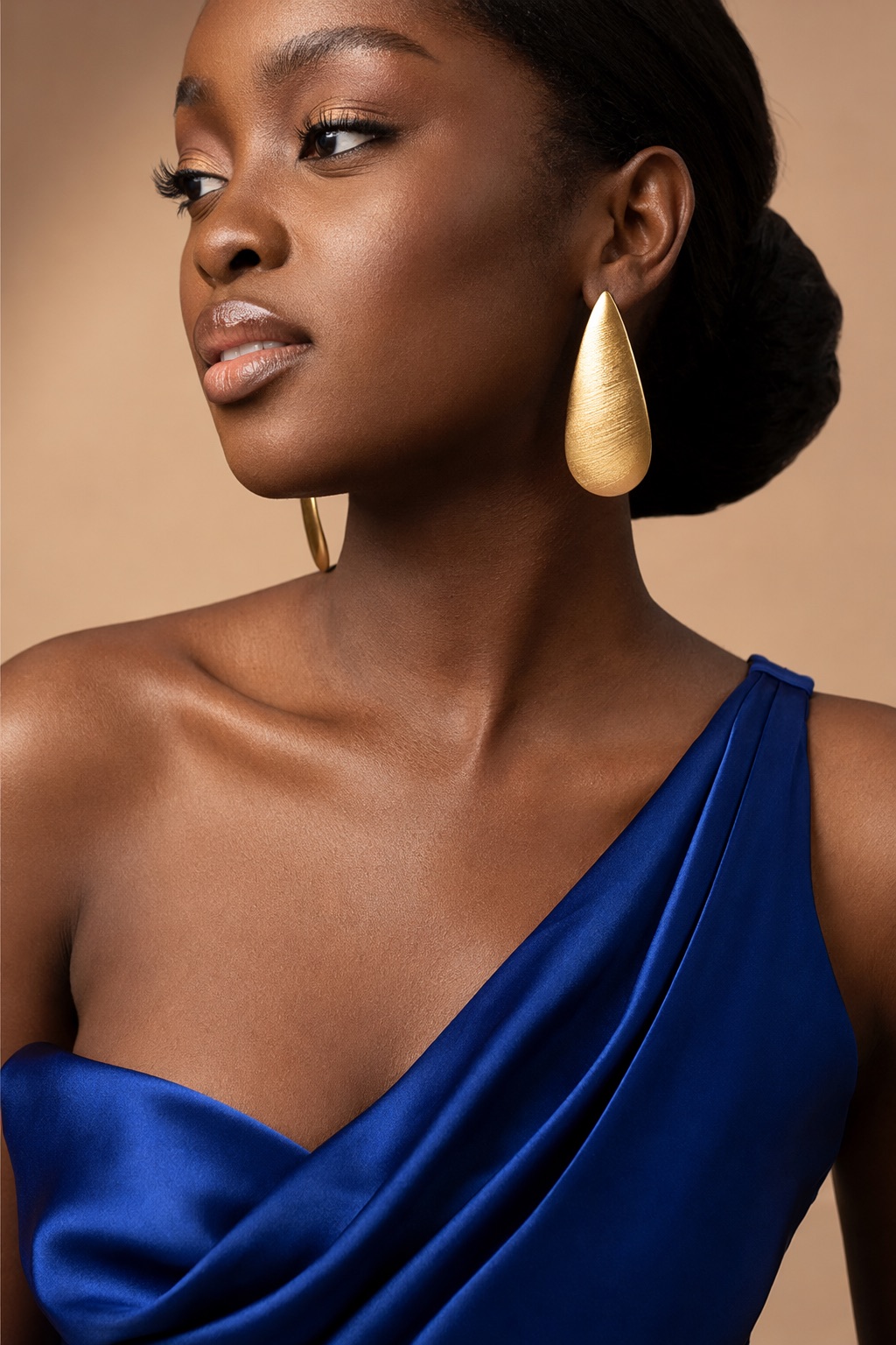 A close frame on the cowl neckline and the gold earring